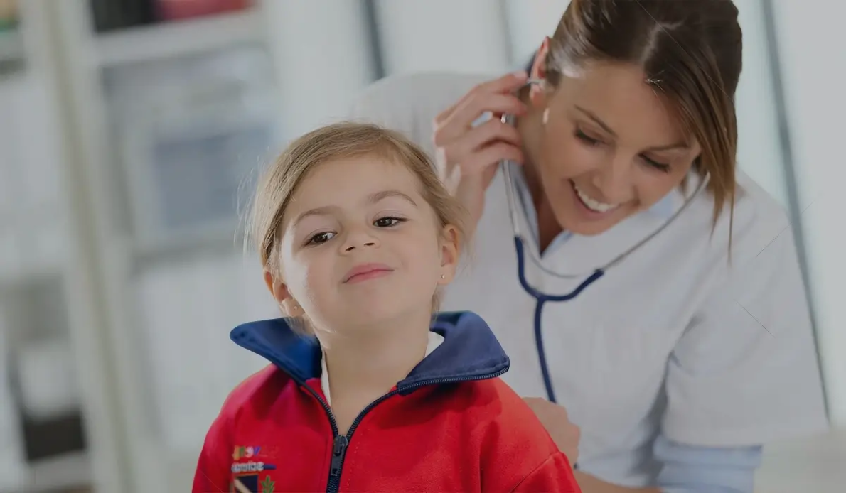 une petite fille dans une école maternelle est auscultée par un médecin