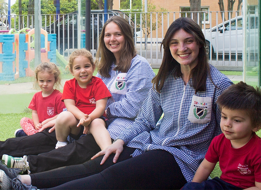 Las becarias Elawen y Jaclyn con sus alumnos en el patio de 5ª Avenida Schools