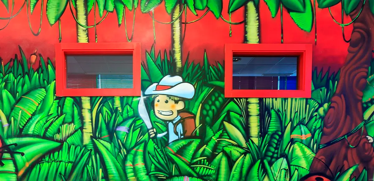 graffiti con niño explorador en la selva sobre pared de una escuela infantil