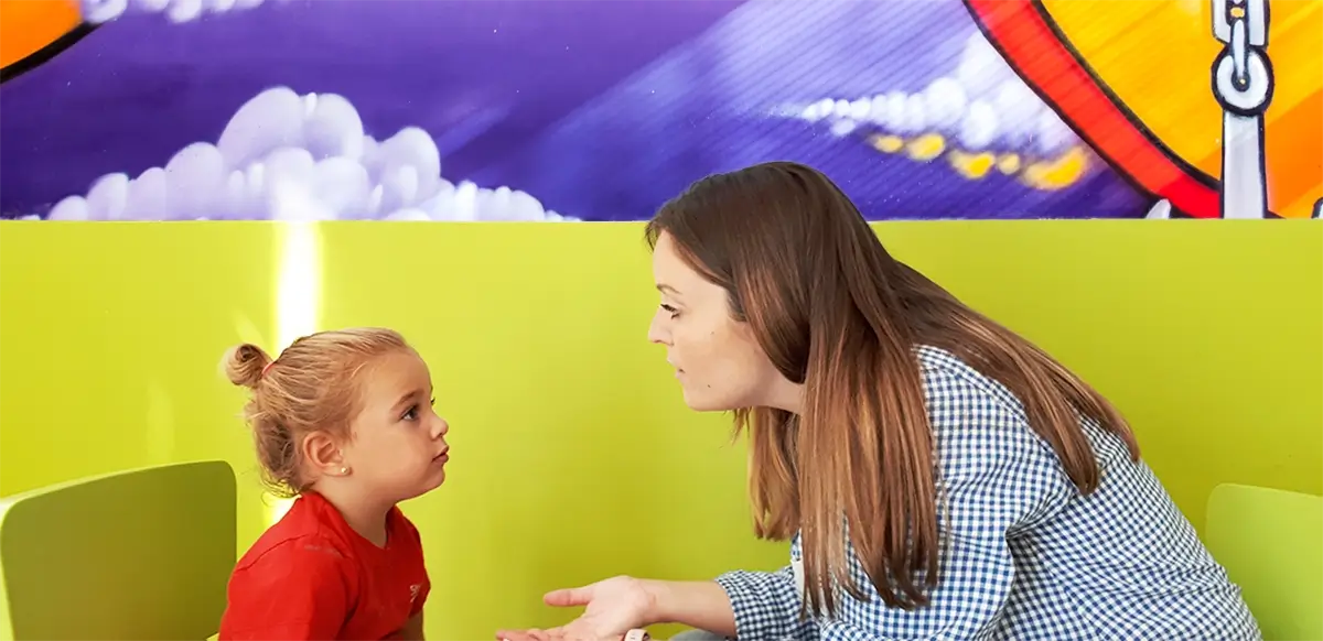 educadora hablando en inglés a una niña pequeña en una escuela infantil