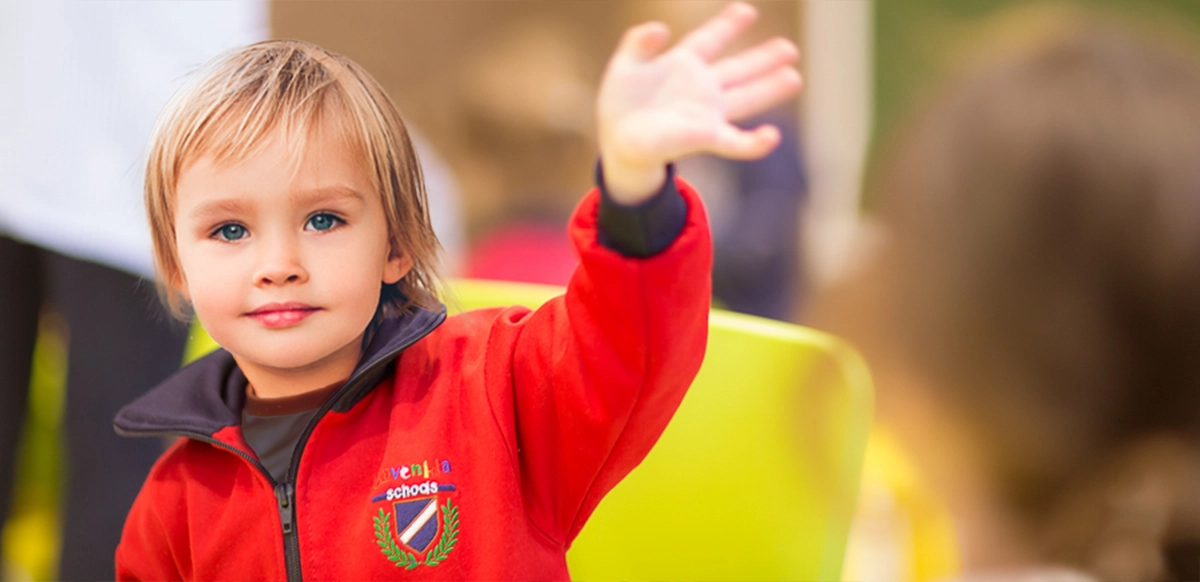 élève d'école maternelle saluant la caméra