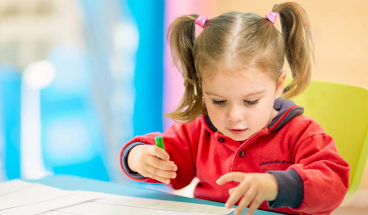 niña con uniforme de escuela infantil dibujando